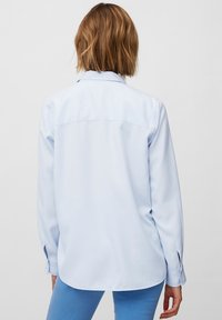 Camicia a maniche lunghe azzurro chiaro con colletto abbottonato, orlo curvo e polsini con un solo bottone. Tessuto liscio con una trama semplice. Vista posteriore mostrata.