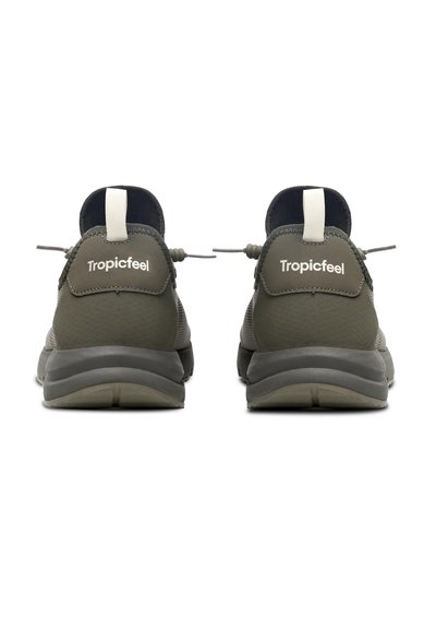 Zapatillas ligeras verdes con un upper de tela texturizada, cordones elásticos y suelas de goma. Logo "Tropicfeel" en el talón en blanco.