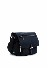 Granatowa torba listonoszka z klapą, główną kieszenią na zamek i przednią kieszenią na zamek. Posiada srebrne elementy i pasek na ramię.