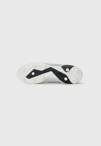 White soccer cleat with a mesh upper, featuring a black zigzag design on the sole with prominent studs for traction.