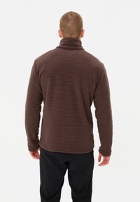 Pullover in pile marrone con colletto alto, motivo a griglia testurizzata e maniche lunghe. Presenta una vestibilità comoda e polsini rifiniti.