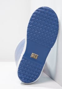 Suela de bota de goma azul con textura en el tread y el número de talla 28 mostrado en el medio, inclinada contra un fondo blanco en la esquina.