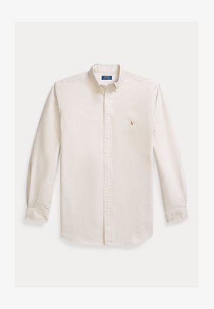 Langermet skjorte med knapper i kremfarget bomullsstoff. Har spredt krage og en liten brodert logo på brystet. Klassisk passform.