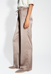 Beige satin wijde broek met elastische tailleband en trekkoord, met een gladde textuur en minimale stikdetails.