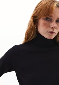 Schwarzer Rollkragenpullover mit weicher Textur, der ein enganliegendes Design und subtile Nahtdetails an den Schultern aufweist.