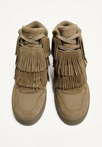 Bruine suede enkellaarzen met gelaagde franjes, textielstof en een gepolsterde kraag voor extra comfort. Rubberen zool voor grip.