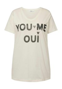 T-shirt color crema a maniche corte con scollatura a V e testo stampato in nero che dice "YOU ♥ ME OUI". Materiale in cotone morbido con vestibilità rilassata.