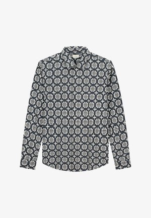 Hosszú ujjas ing sötétkék anyagból, geometrikus fehér mintázattal, amely köröket és kereszteket tartalmaz, hegyes gallérral és gombos mandzsettákkal.