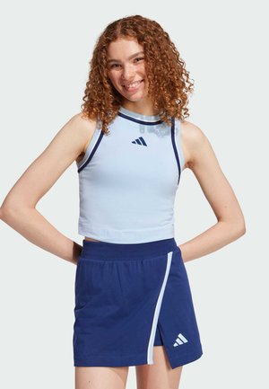 Top corto atletico azzurro chiaro con rifiniture blu scuro, abbinato a una gonna blu scuro con una striscia laterale bianca e il logo Adidas.
