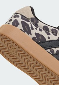 Sneaker mit beiger Gummisohle, schwarzem und grauem Leopardenmuster-Stoff, beiger Wildlederferse und schwarzen Lederstreifen.