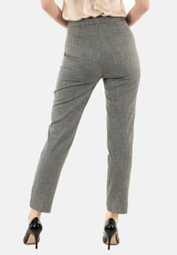 Pantaloni a quadri grigi con vestibilità sartoriale, dotati di tasche posteriori e design elegante. Abbinati a scarpe con tacco alto nere.