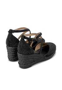 Sandali wedge neri con texture intrecciata, abbelliti con rivetti sulla parte superiore e cinghie alla caviglia incrociate con chiusura a fibbia.