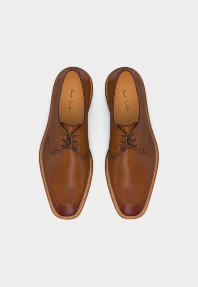 Ζευγάρι καφέ δερμάτινων επίσημων παπουτσιών με κορδόνια, με τετράγωνες μύτες και επενδύσεις εσωτερικά με λογότυπο, σε λευκό φόντο.