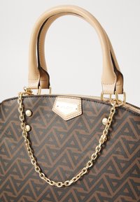 Braune handgefertigte Handtasche aus strukturiertem synthetischem Material, mit beigen Ledergriffen, goldfarbener Kettenakzent und Markenzeichen-Detail.