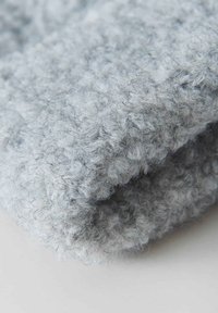 Soft gray knitted fabric featuring a textured, looped pattern. The material appears fuzzy with a slightly irregular surface.