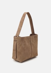 Sac à main moyen en daim marron avec une large bandoulière unique et des coutures verticales subtiles sur fond blanc.