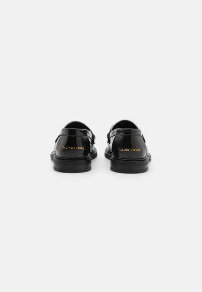 Musta kiiltävä nahkakengät pyöristetyllä kärjellä, soljella varustettu yksityiskohta ja kontrastoiva "FILLING PIECES" -brändäys kullalla kantapäässä.