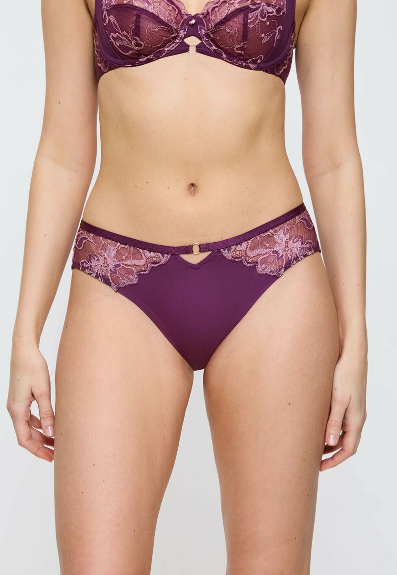 Fioletowy bikini z koronką i tkaniną, ozdobione kwiatowym wzorem oraz dekoracyjnymi elementami z przodu. Posiada średni stan i przezroczyste akcenty.