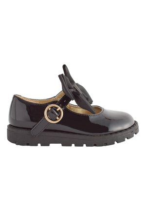 Chaussure Mary Jane en cuir verni noir avec une semelle épaisse, une bride à boucle dorée et un nœud décoratif en tissu noir sur le dessus.