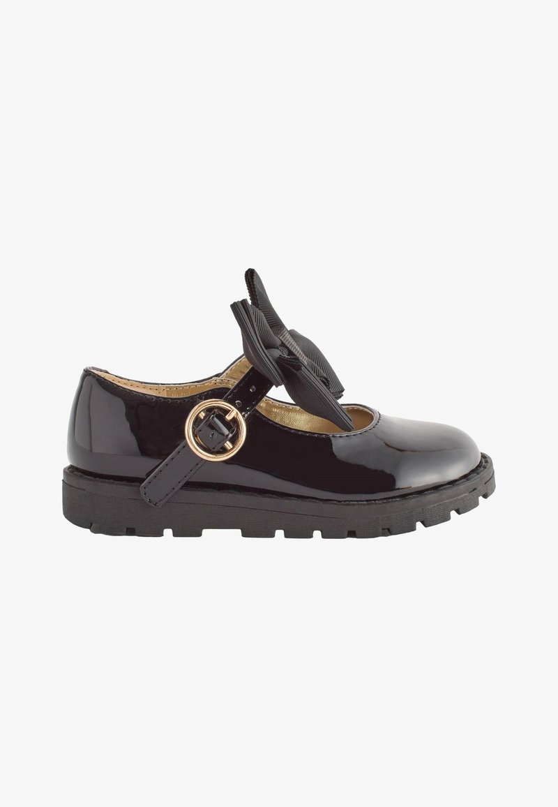 Chaussure Mary Jane en cuir verni noir avec une semelle épaisse, une bride à boucle dorée et un nœud décoratif en tissu noir sur le dessus.