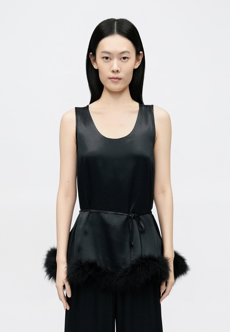 Top fără mâneci din satin negru, cu decolteu rotund și cordon la talie, având o margine din blană neagră pufoasă în partea de jos.