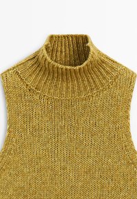 Maglione giallo lavorato a maglia, senza maniche e con un alto colletto a costine. Tessuto texture con cuciture visibili e vestibilità rilassata.