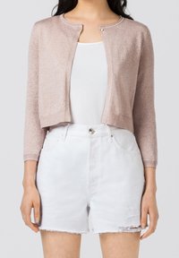 Cardigan rosa corto in maglia con colletto rotondo, maniche lunghe e un bottone davanti, abbinato a pantaloni corti in denim bianco con effetti distressed.