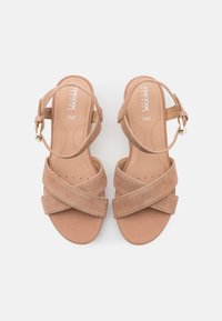 Sandali in suede beige con cinturini incrociati, chiusura alla caviglia con fibbia e soletta imbottita. Progettati per il massimo comfort con plantare forato.