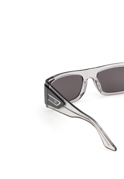 Gafas de sol de acetato transparente con lentes rectangulares oscuras y detalles en negro y plata en las varillas.