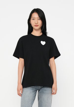 T-shirt di cotone nero con maniche corte, caratterizzato da un logo a forma di cuore bianco con la scritta "Hope" sul lato sinistro del petto. Vestibilità casual e rilassata.
