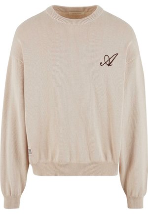 Beige strikket sweater med rund hals, ribbede manchetter og kant. Har et brunt broderet logo på forsiden og et label på siden.
