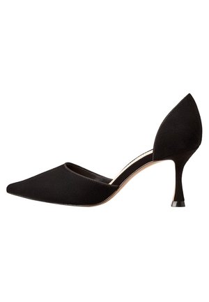 Sorte højhælede sko lavet af ruskind med spids tå, udskårne sider og en slank hæl med en sort akcent på bunden.