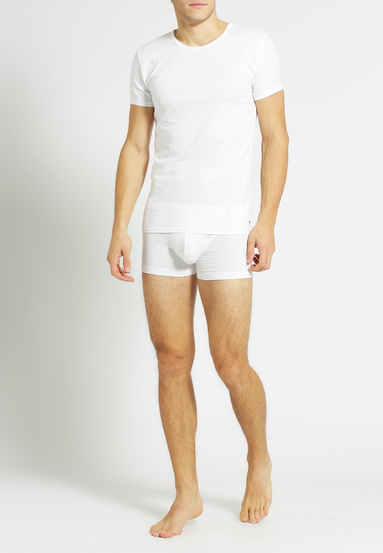White cotton crew neck t-shirt paired with white boxer briefs. The t-shirt has short sleeves and a smooth texture. Model is barefoot.