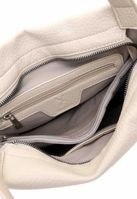 Beežikate tekstuuriga nahast käekoti siseosa, kus on mitu tõmblukuga taskut ja kangast vooder.