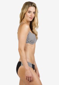 Zwart-witte zigzagpatroon bikini-top met dunne banden, gecombineerd met effen zwarte bikini-botten en een aansluitend ontwerp.