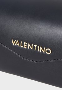 Čierna kožená kabelka s zlatým logom "VALENTINO", hladkým povrchom a jemným šitím pozdĺž okraja.