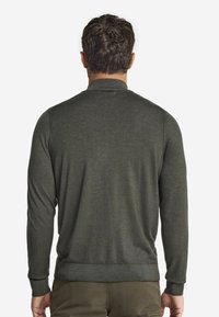 Ciemnozielony sweter z długim rękawem o gładkiej teksturze, z prążkowanymi mankietami i dołem. Minimalistyczny design, bez widocznych logotypów czy wzorów.