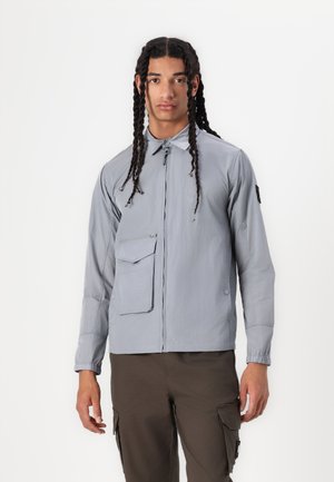 Light gray, lightweight jacket with a zip front, a chest pocket, and elastic cuffs. Fabric has a smooth texture with minimal stitching details.