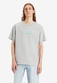 Camiseta gris de manga corta de algodón, con un logo multicolor de "LEVI'S" en el pecho, de corte relajado y cuello redondo.