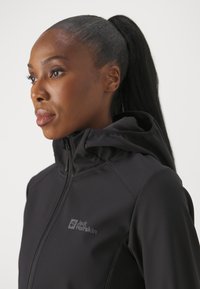 Giacca nera con zip e cappuccio, realizzata in tessuto liscio. Presenta un logo discreto sul petto e un design aderente.