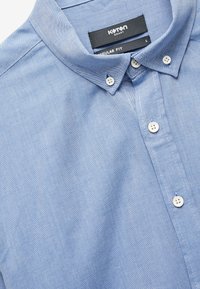 Jasnoniebieska koszula zapinana na guziki wykonana z bawełny, o regularnym fasonie, klasycznym kołnierzyku i białych guzikach. Miękka w dotyku i z delikatnym wzorem.