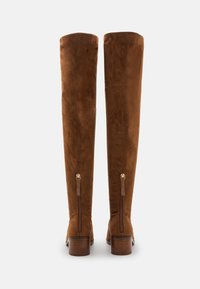 Brune nubuck over-the-knee støvler med firkantet tå, stablet hæl og lynlåse i siden. Glat tekstur og minimalistisk design, velegnet til forskellige outfits.