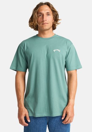 T-shirt di cotone verde menta con maniche corte, scollatura rotonda e piccolo logo bianco sul petto. Design semplice con una vestibilità rilassata.