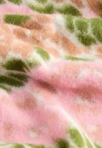 Sanfter Wollstoff mit einer flauschigen Textur in abstrakten Mustern in Rosa, Grün, Braun und Weiß sowie sanften Falten.