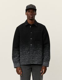 Schwarze und graue Gradient-Jacke mit Knopfleiste, Kragen und Brusttasche. Aus strukturiertem Stoff, auf einem Modell vor einem neutralen Hintergrund präsentiert.