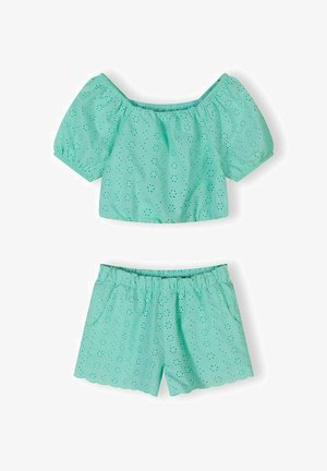 Ținută turcoaz în două piese cu modele florale perforate, constând dintr-un top scurt cu mâneci bufante, descoperit pe umeri, și pantaloni scurți cu talie elastică și margini festonate.