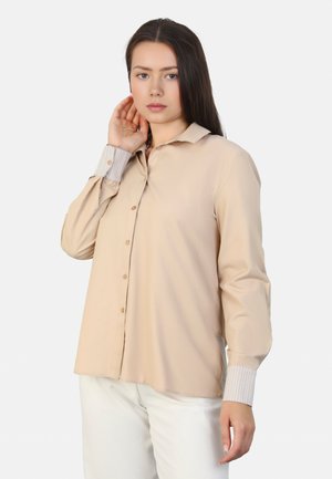 Beige košilová košile s límečkem, s proužkovanými manžetami a měkkou strukturou. Navržena s uvolněným střihem a dlouhými rukávy.
