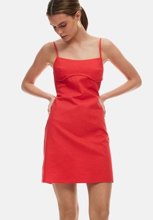 Abito mini in lino rosso con scollo a cuore, spalline sottili regolabili e silhouette aderente. Presenta una texture liscia e senza pattern.