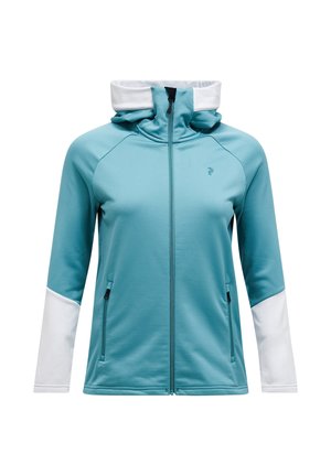 Chaqueta azul verdosa con cremallera y cuello alto, mangas blancas y bolsillos laterales. Tejido suave y elástico con una textura lisa y un ajuste atlético.