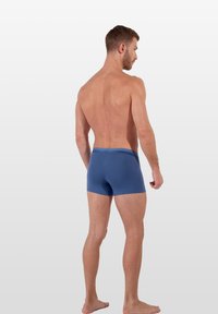 Mörkblå boxershorts i mjukt tyg. Har en elastisk midjeband med logotyp och en figursydd design som framhäver baksidan och benen.